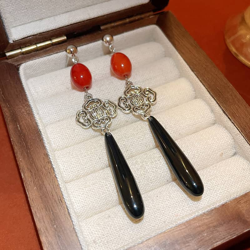 Elegant anger teardrop earrings featuring red beads and silver accents in a wooden box