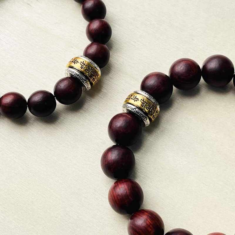 Close-up of antique rosewood mala bracelet with silver and gold accents for mindfulness and meditation