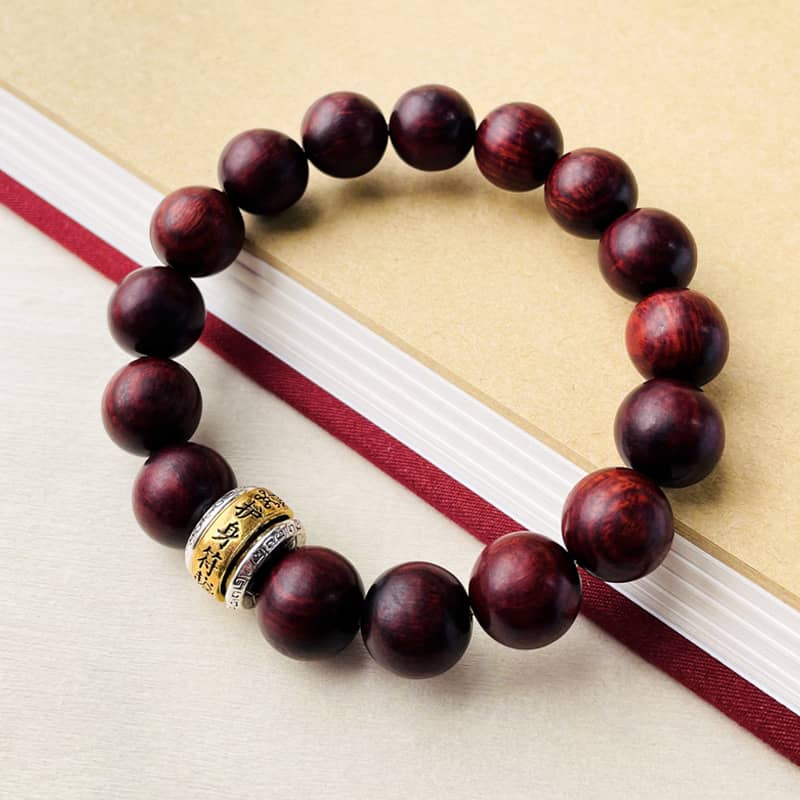 Antique rosewood mala bracelet featuring warm wooden beads and a decorative silver accent