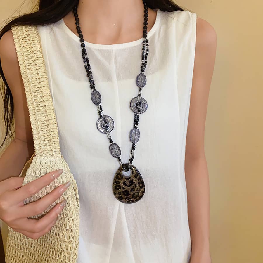 Chic model wearing a black leopard pendant necklace with textured beads and a stylish outfit