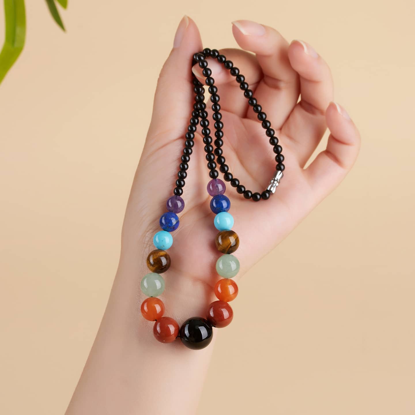 Hand holding a crystal necklace for stress and self care featuring colorful beads for calming energy