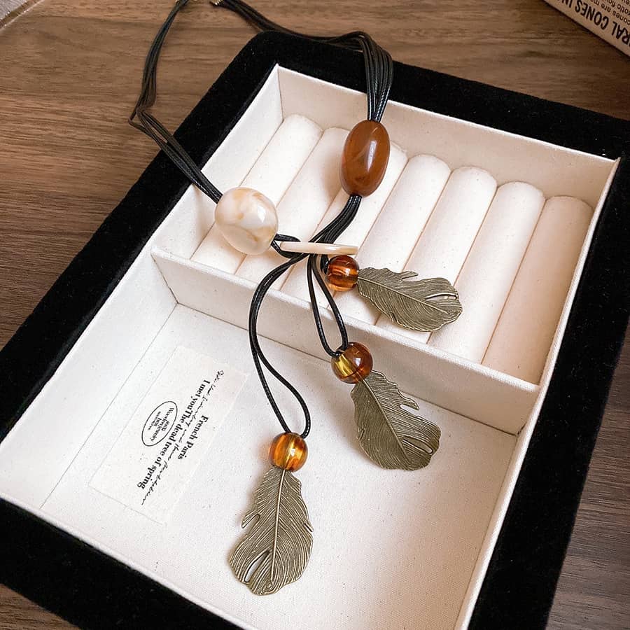 Angry earth pendant necklace featuring leaves and colorful beads on a black cord