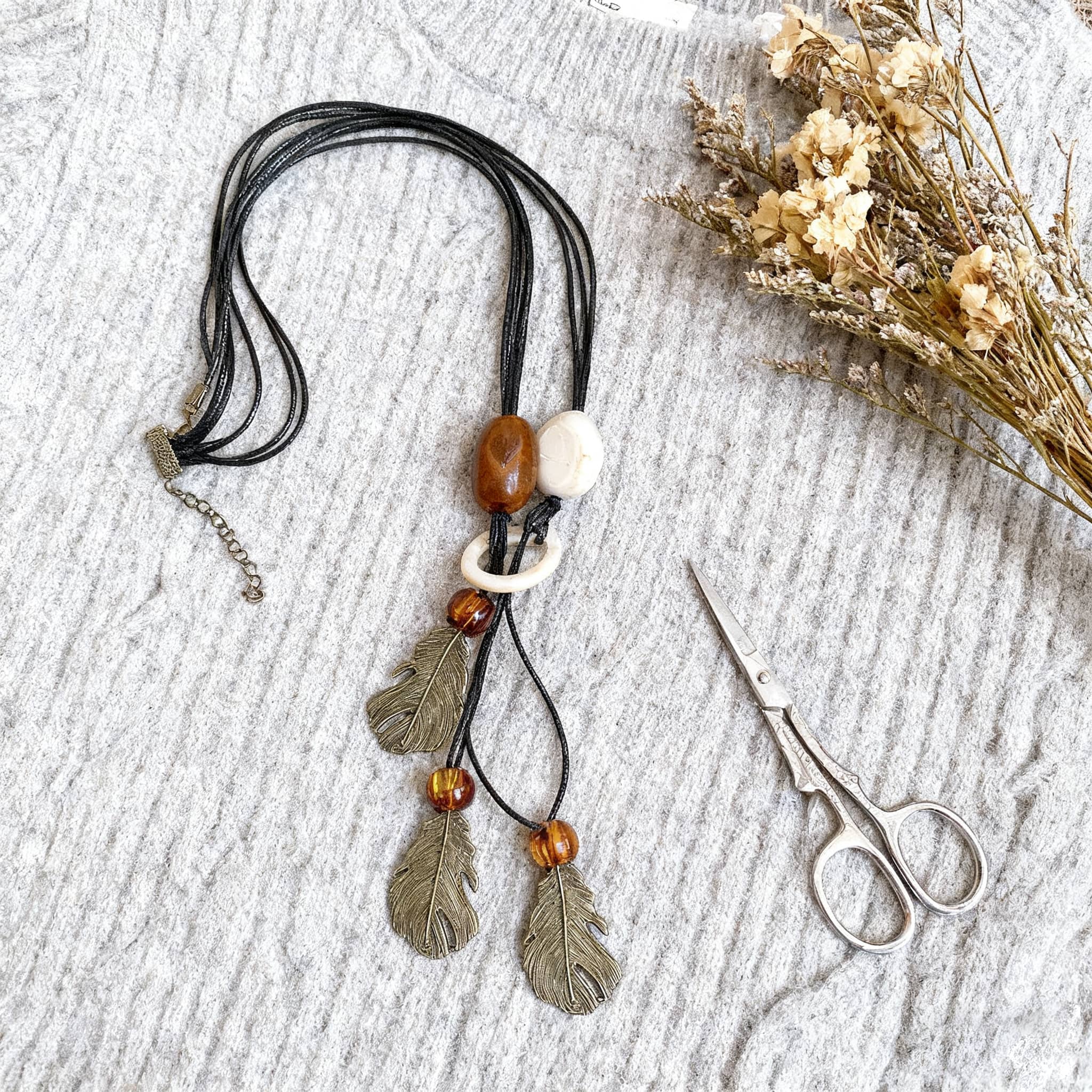 Trendy earth pendant necklace with natural beads and feather accents for a bohemian look