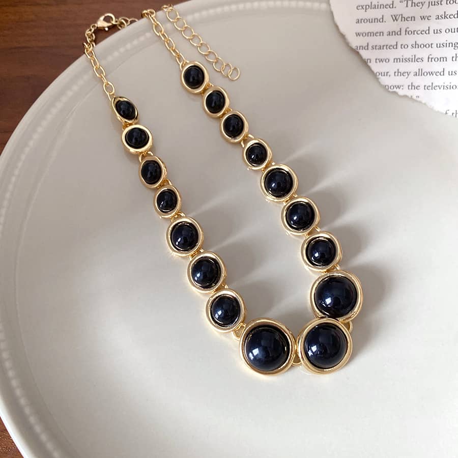 Elegant geometric resin pendant necklace featuring black gems set in gold for a stylish look