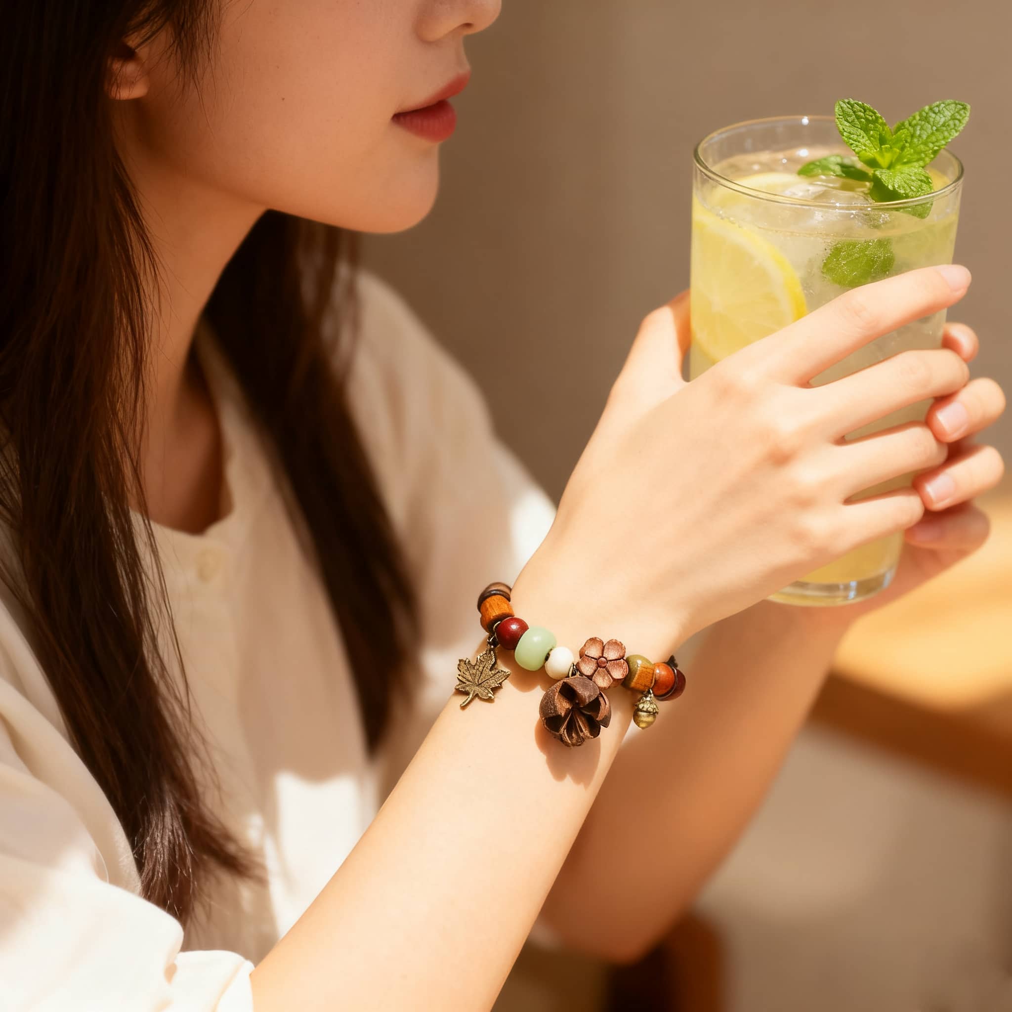 Woman wearing a handcrafted berry and wood bracelet while holding a refreshing beverage
