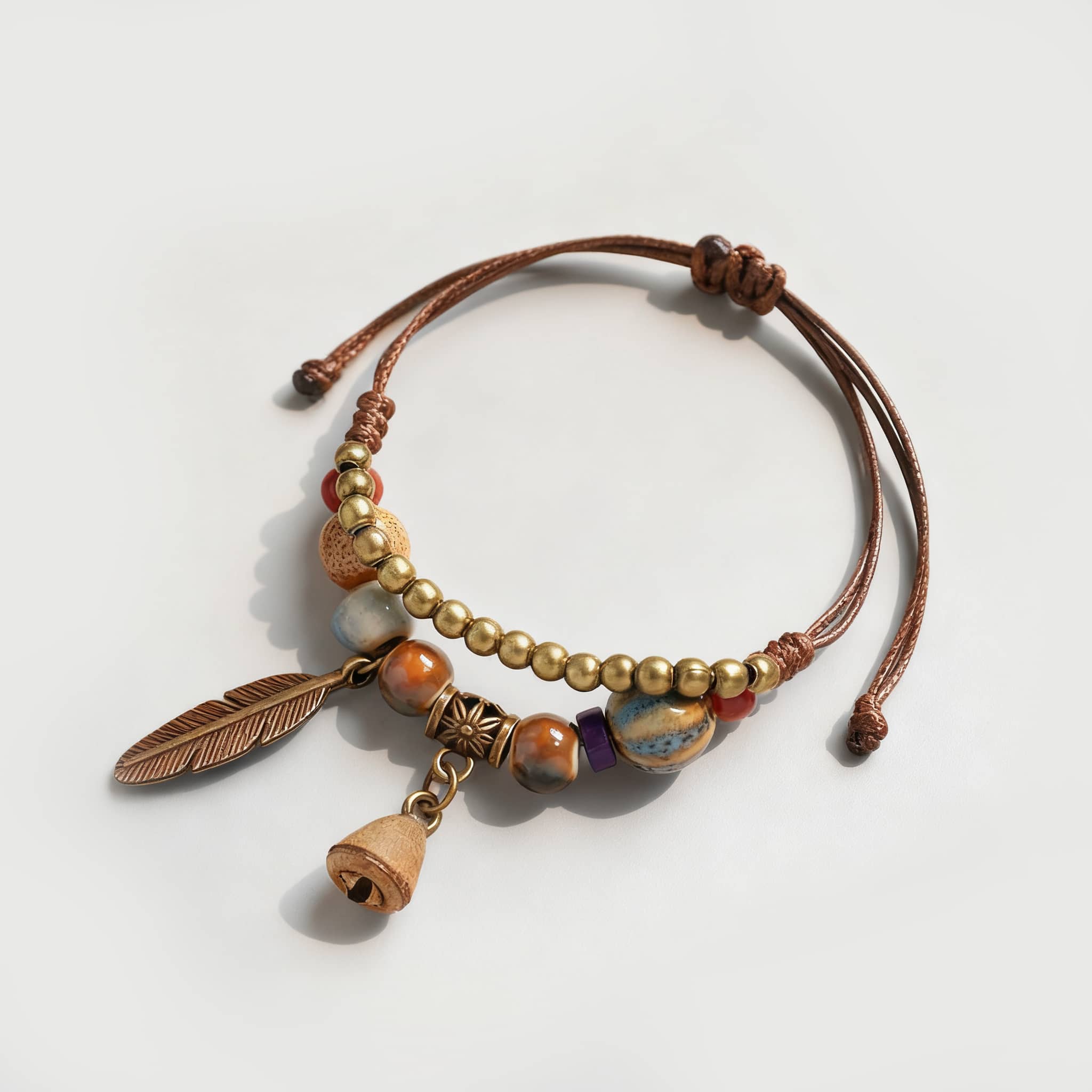 Handmade bell and bead bracelet featuring colorful beads and a decorative feather charm