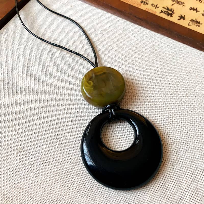 Angry resin pendant necklace for mindfulness featuring a black and green design with a circular shape