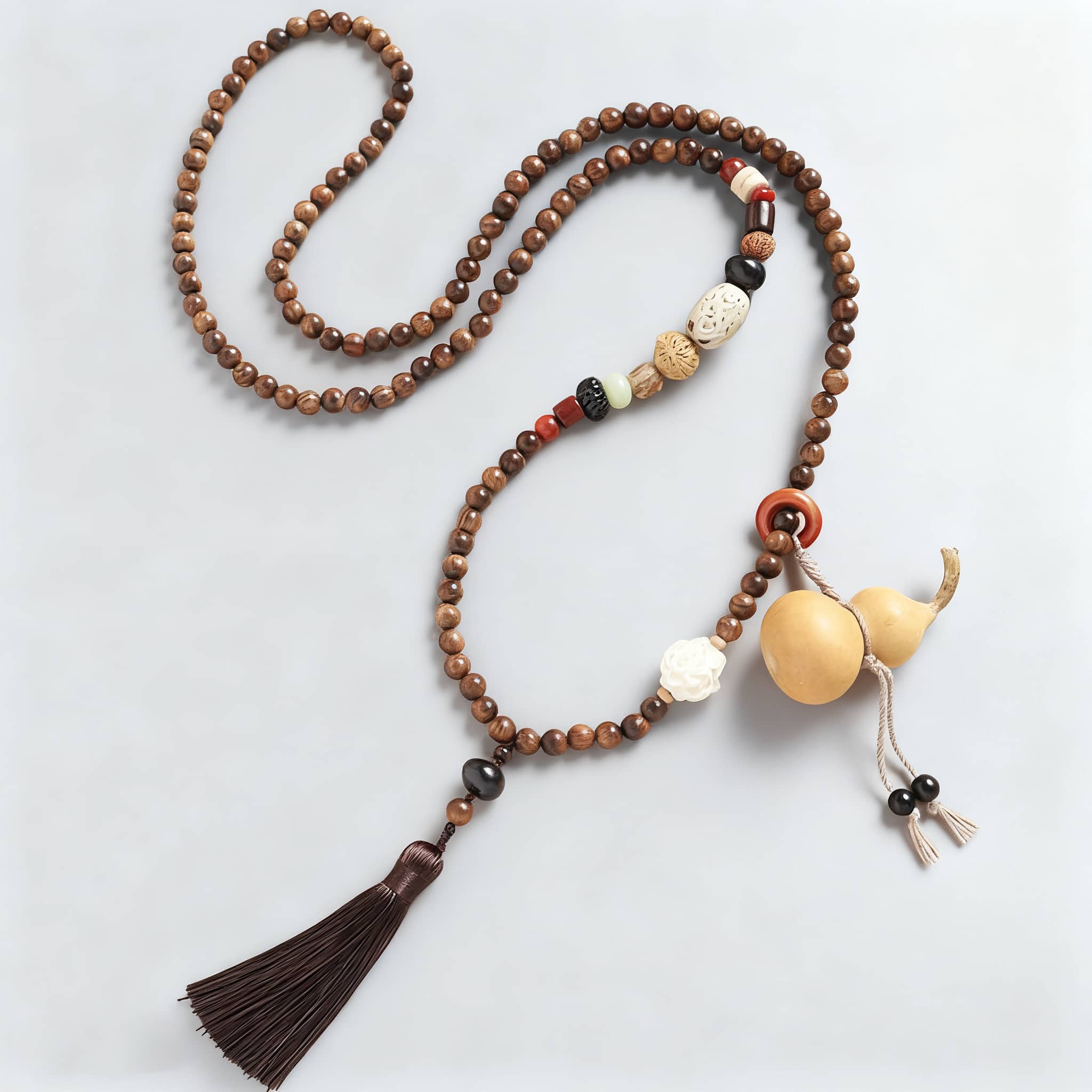 Calm necklace featuring a sandalwood bead cross-body chain with decorative tassel and unique elements