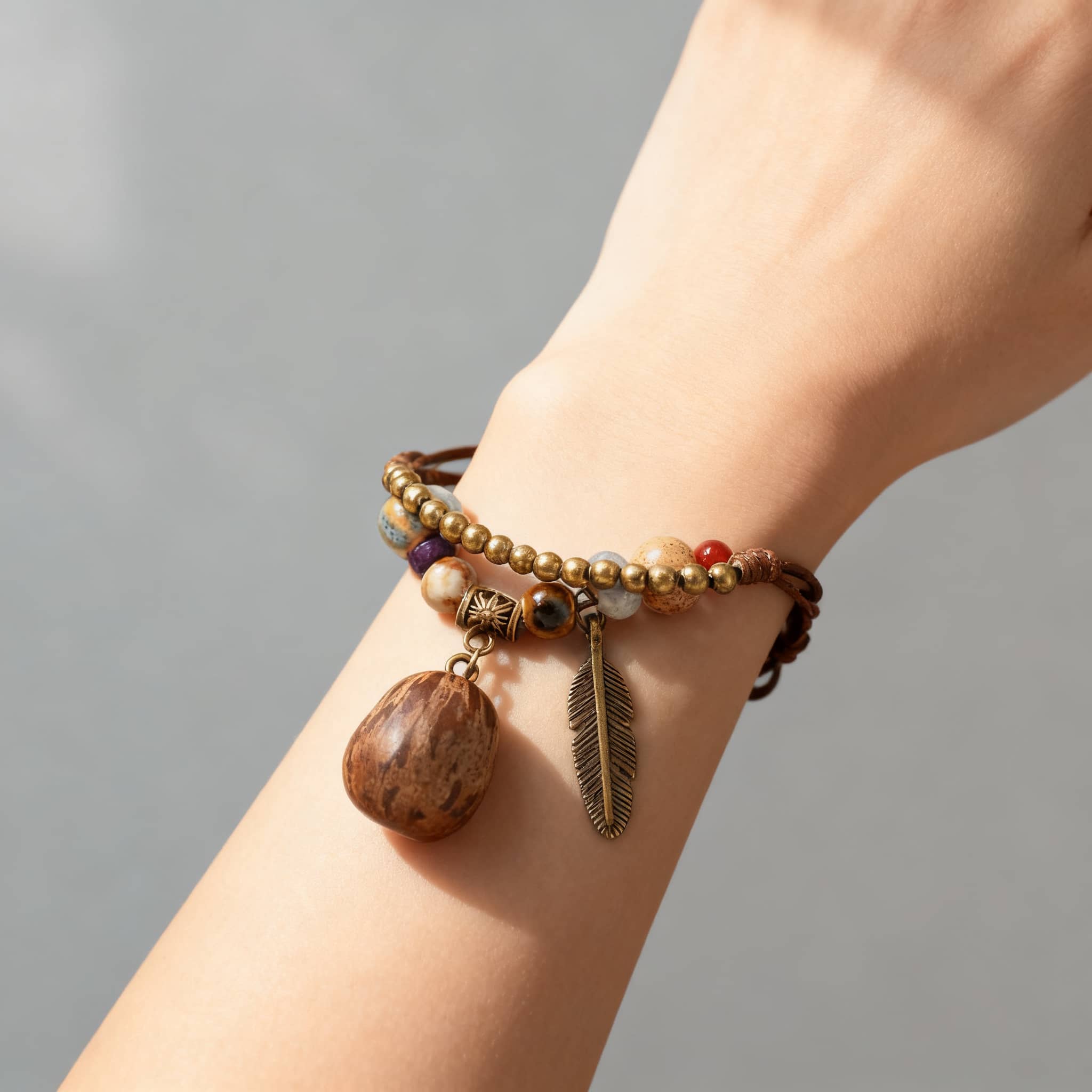 Textured berry charm bracelet featuring wooden beads and a feather pendant for a bohemian look