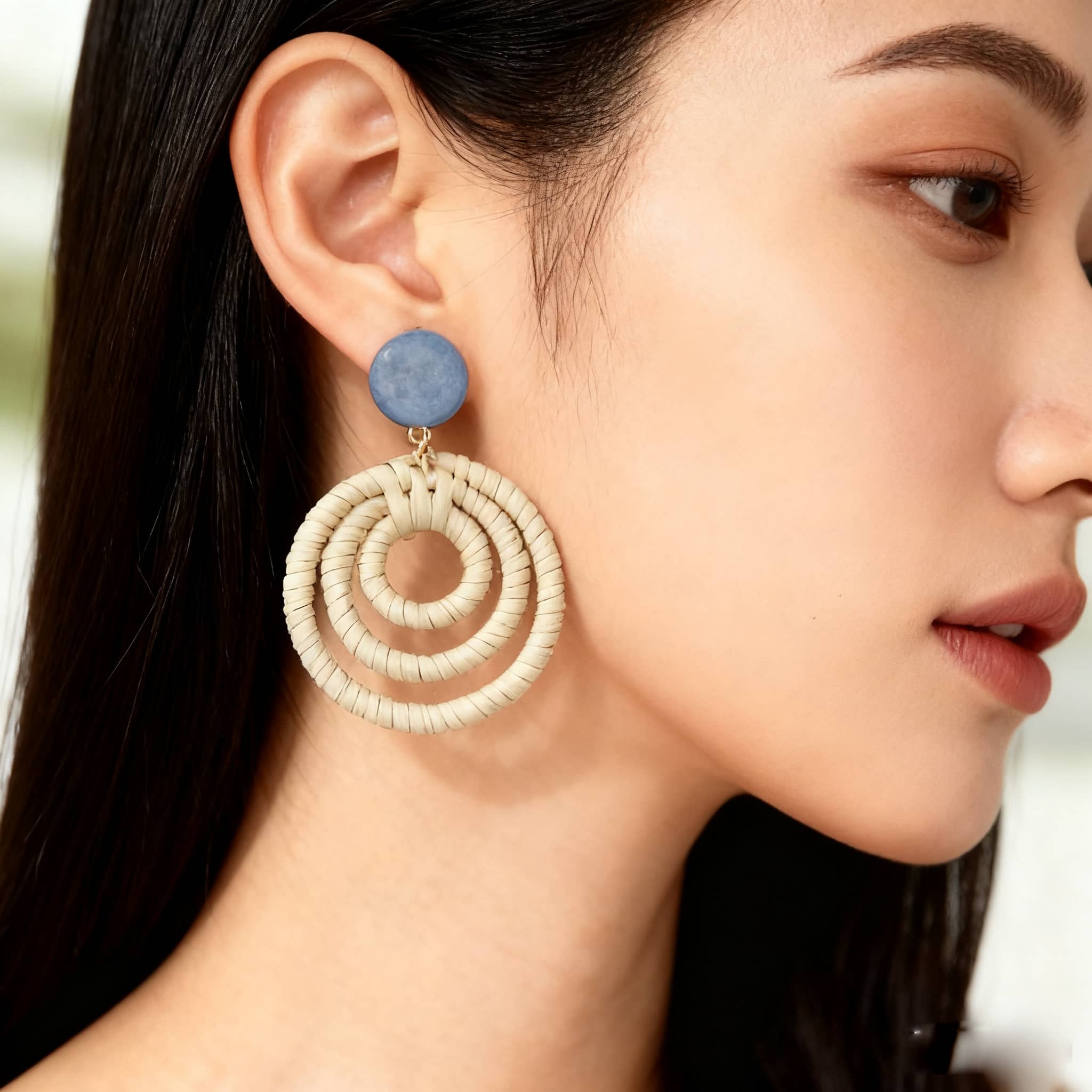Woven bamboo statement earrings with a circular design and blue accent, perfect for stylish outfits
