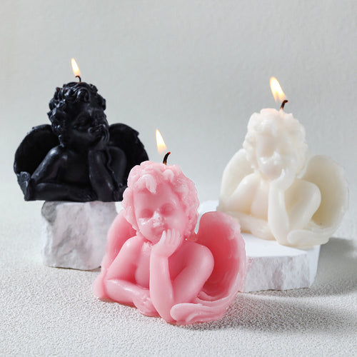 Set of black, pink, and white angel sculpture candle designs with detailed wings and relaxed pose