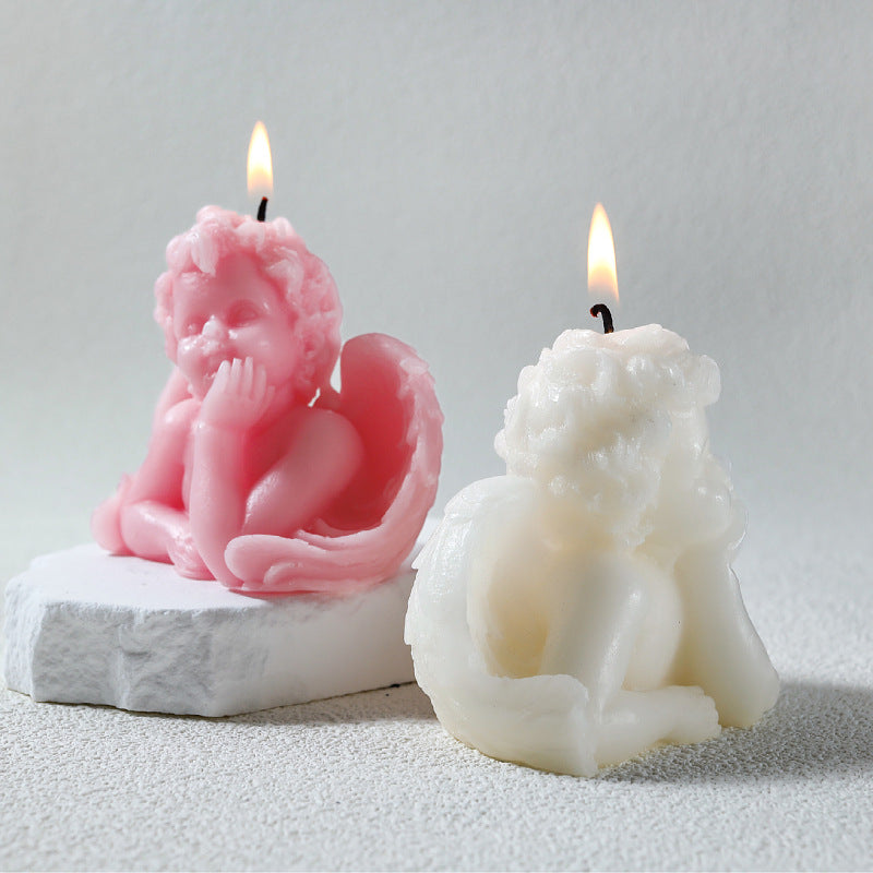 Pink and white angel sculpture candle set with detailed wings and curly hair, lit wicks