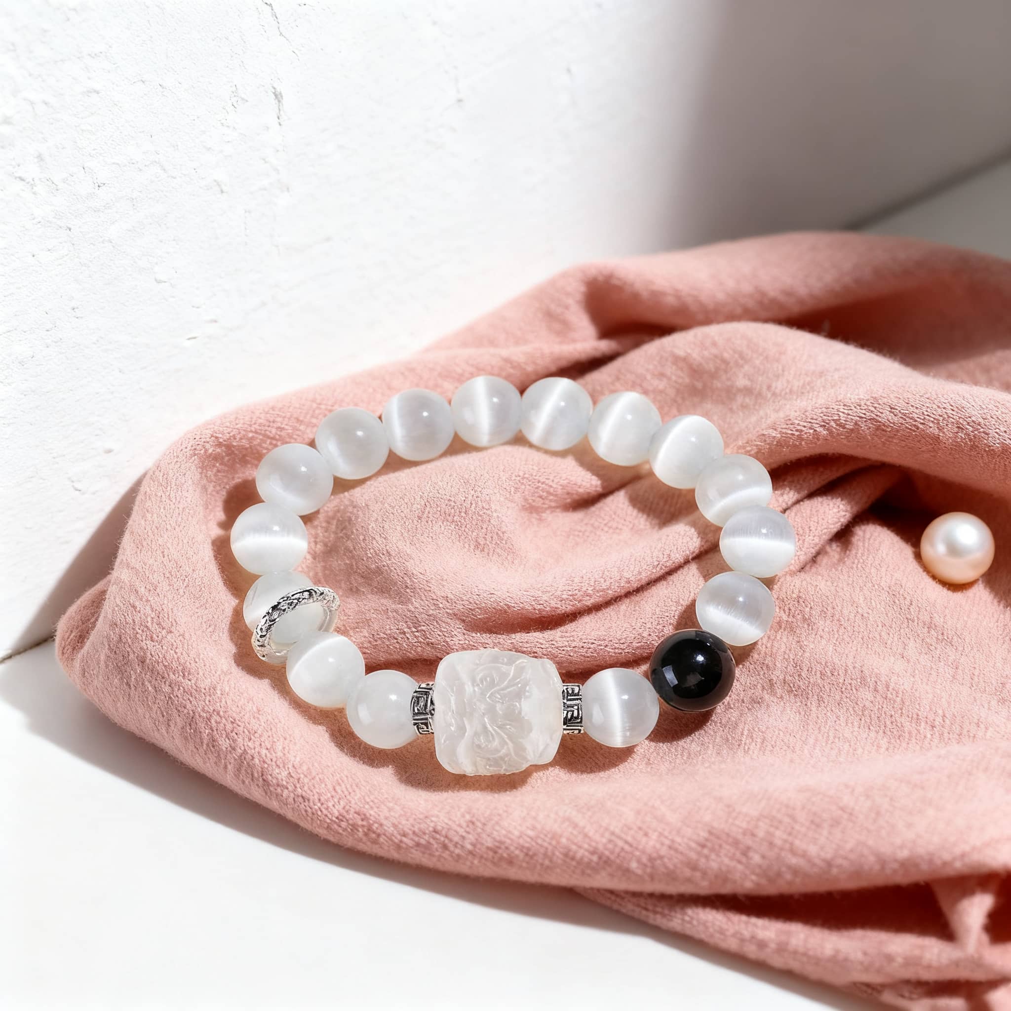 Anxiety relief bracelet with white beads, a black stone, and a decorative centerpiece for stress management