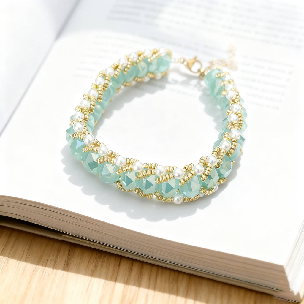 Aqua glass and pearl bracelet with golden accents displayed on an open book