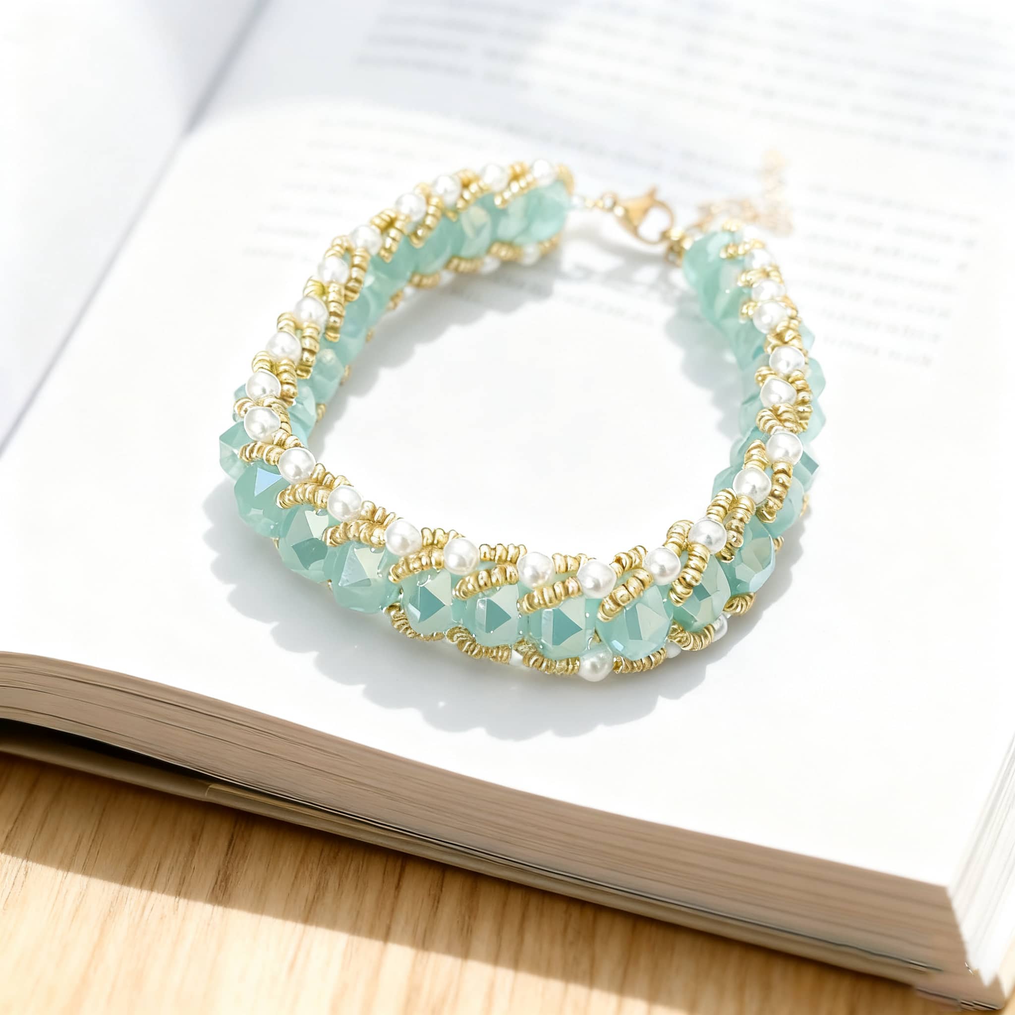 Aqua glass and pearl bracelet with golden accents displayed on an open book