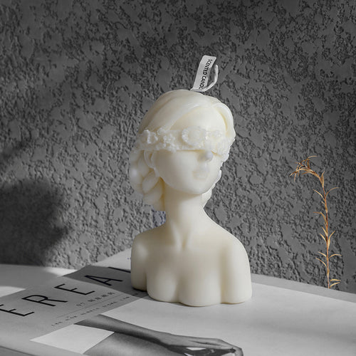 White bust sculpture aromatherapy art candle gift with floral blindfold on textured background