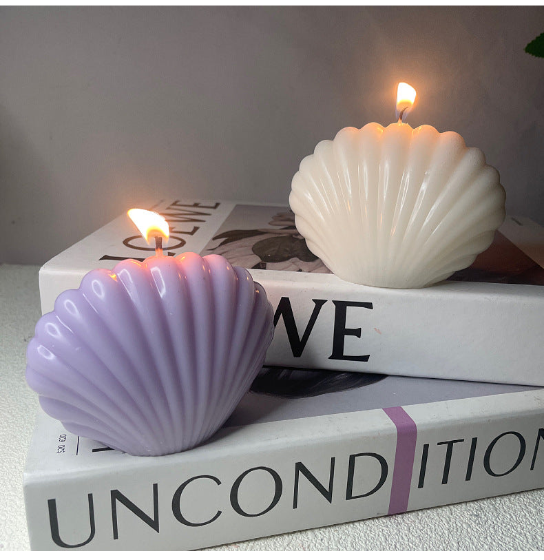 White and lavender aromatherapy shell candle set burning on stacked books for home decor