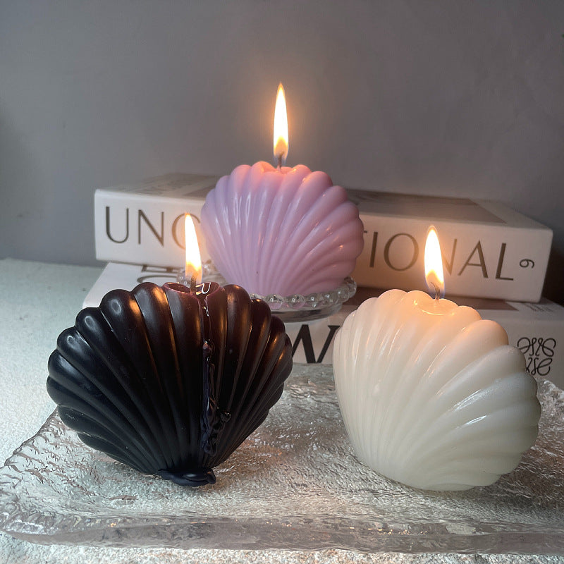 Three lit aromatherapy shell candles in black white and pink colors on a glass tray