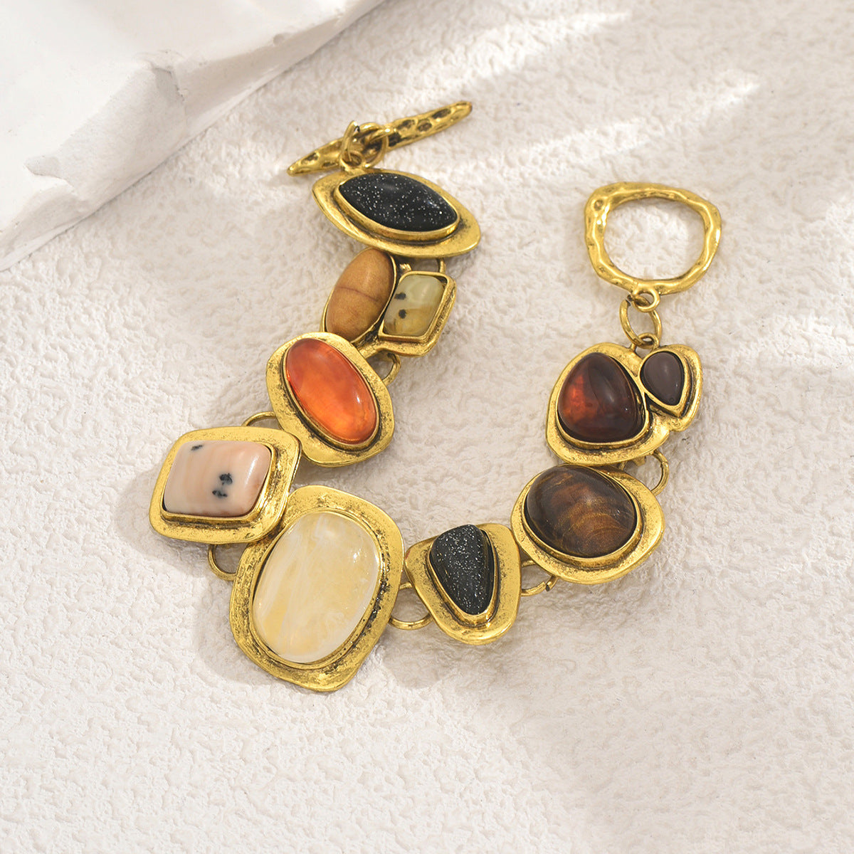 Gold link multicolor gemstone bracelet with assorted cabochon stones in black orange cream and brown
