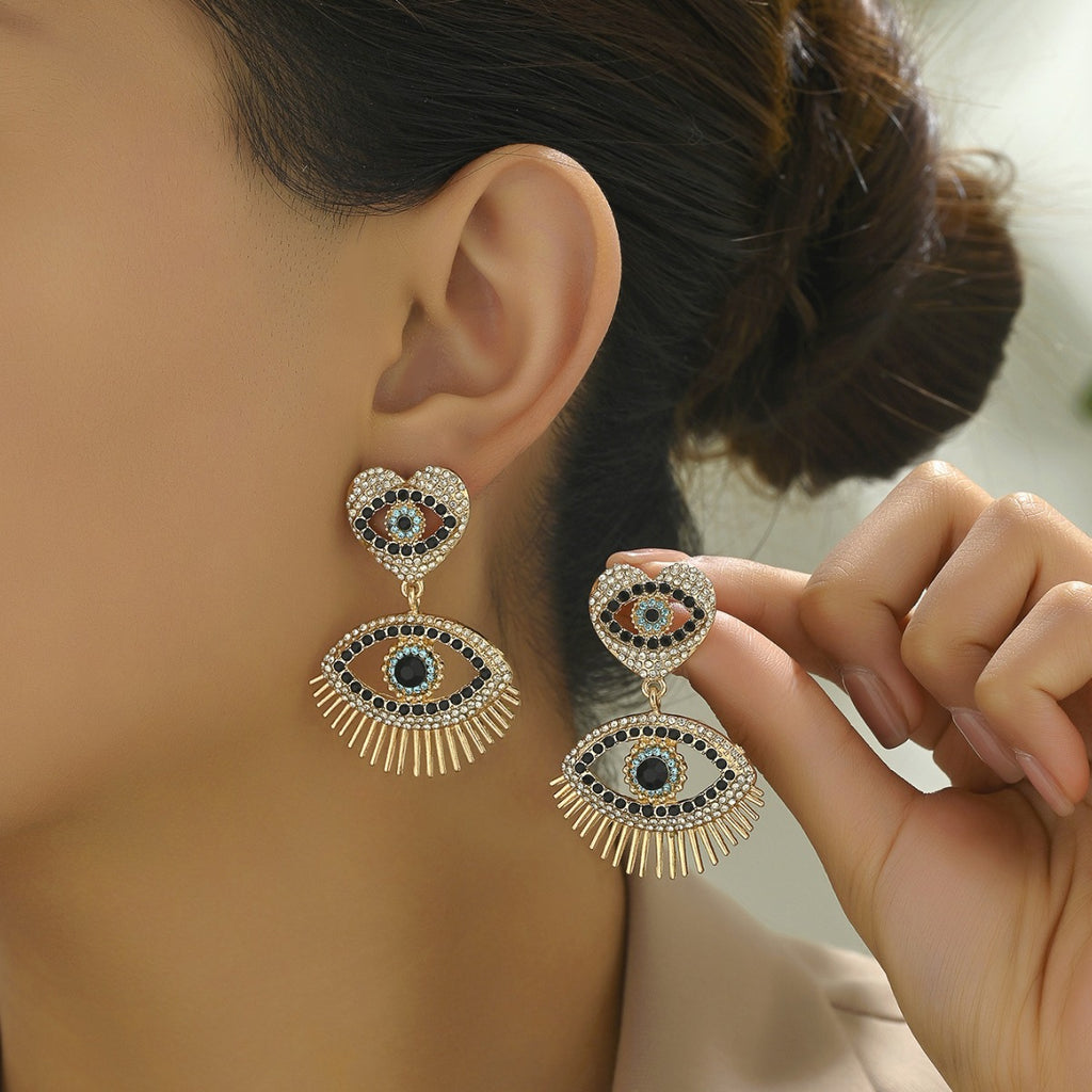 Gold heart angel eye stud earrings with black white crystals and sunray fringe shown on model ear