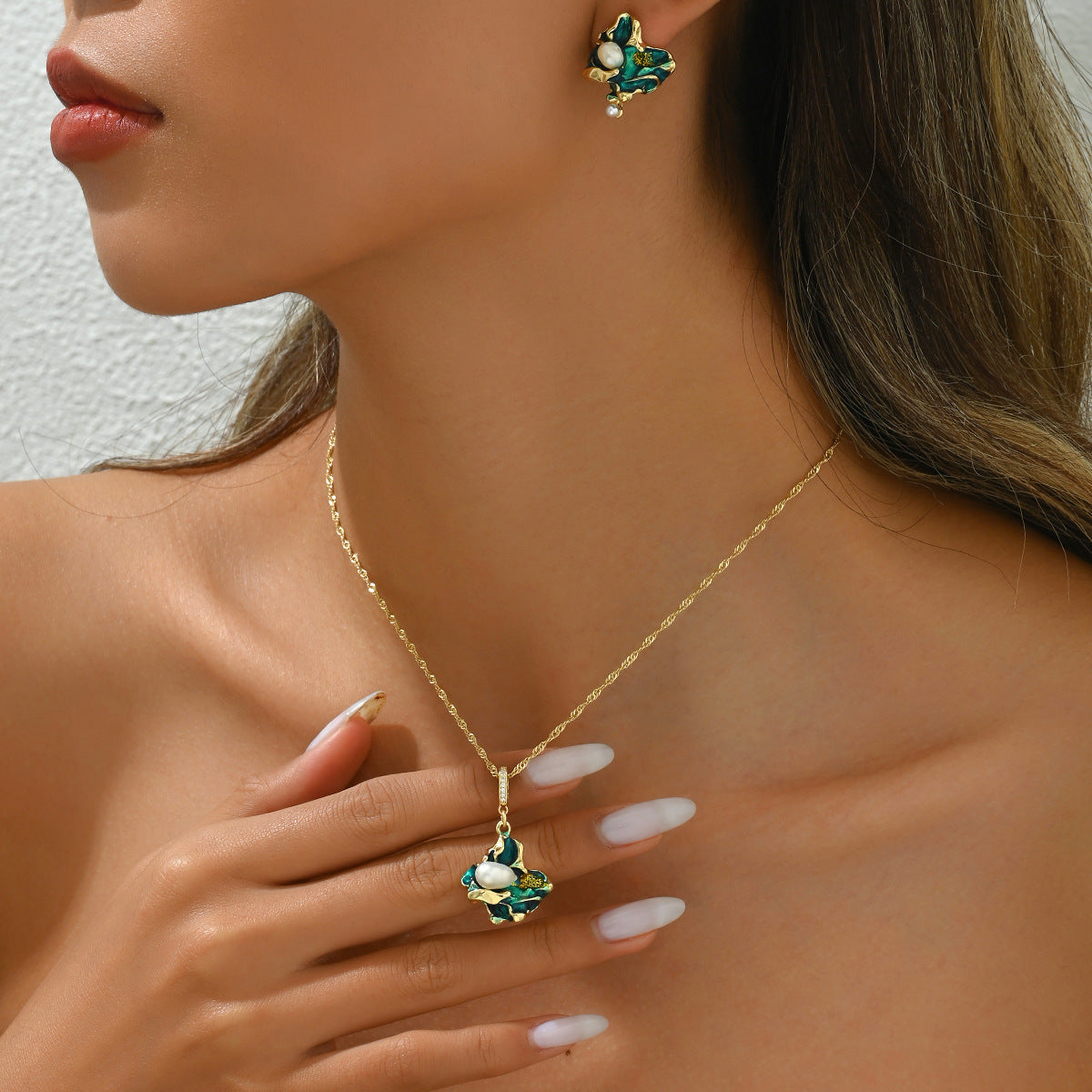 Model wearing lake shaped pearl jewelry set gold chain necklace with green enamel leaf pendant and matching earring
