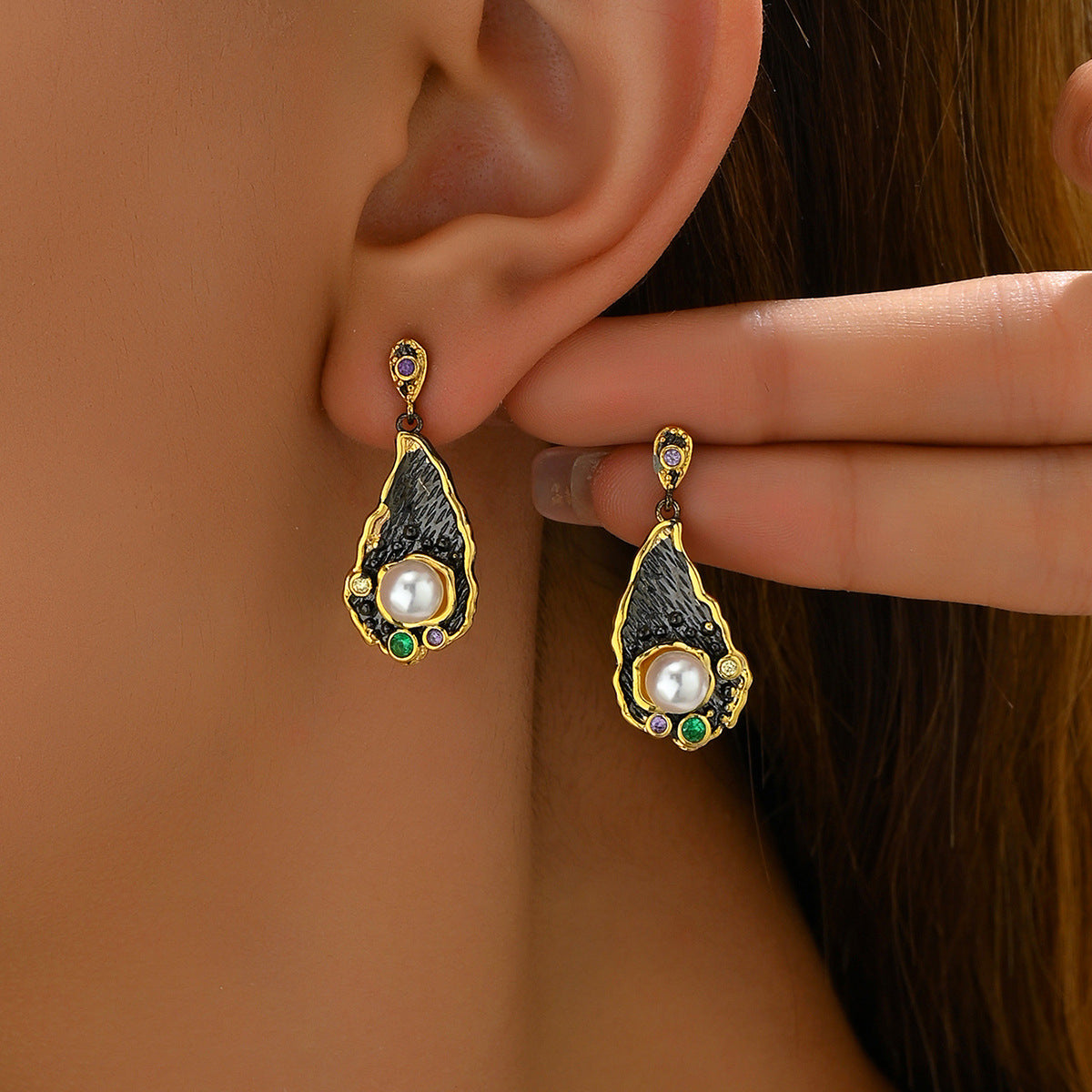 Gold teardrop zircon statement earrings with black textured interior and central pearl with green and purple accents