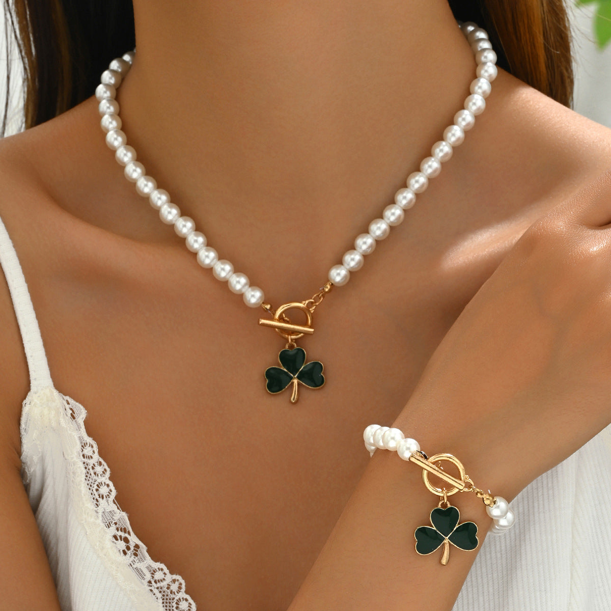 Model wearing heart and clover pearl jewelry set with gold toggle clasp and green enamel clover charms