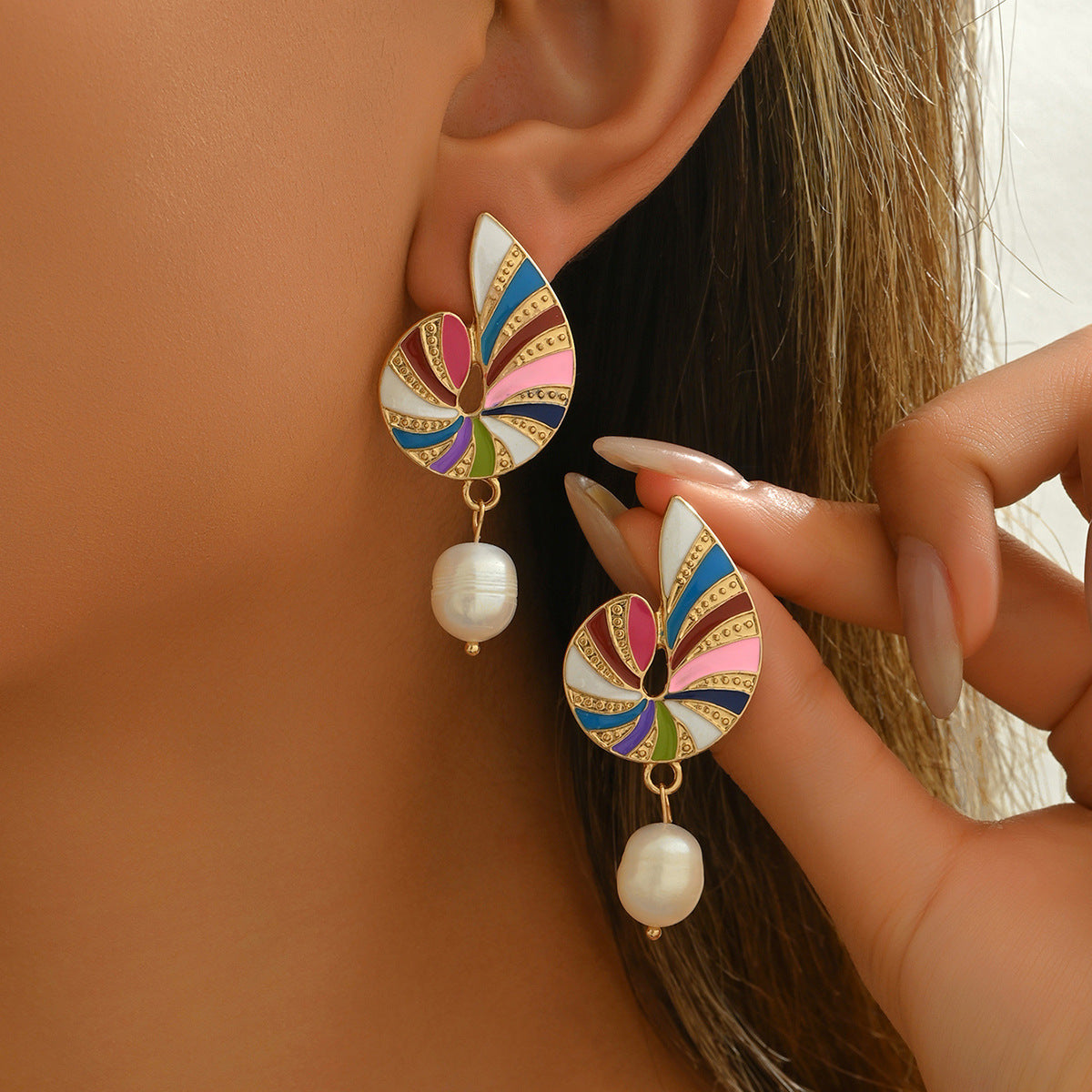 Gold swirl enamel earrings with multicolor segments and dangling pearl worn closeup joyful enamel jewelry gift