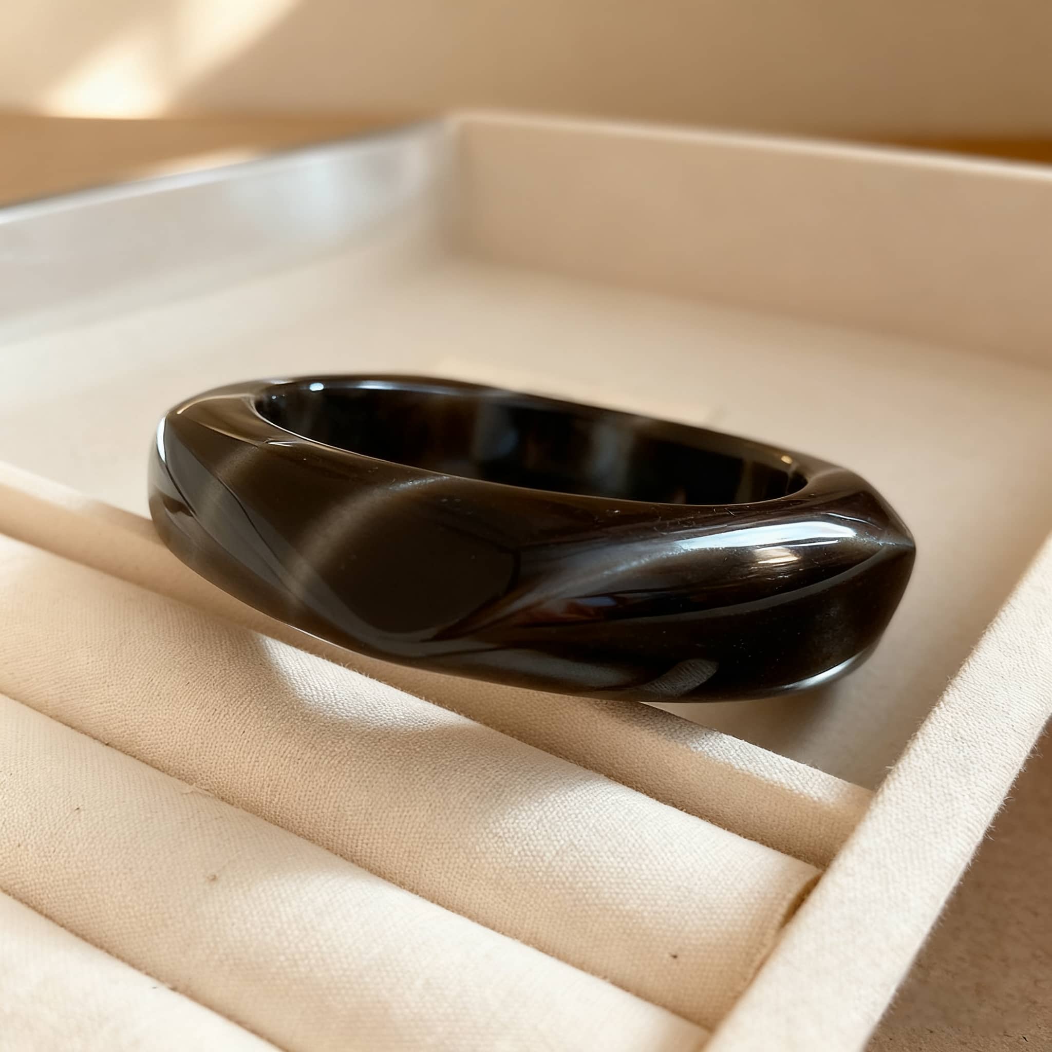 Elegant black cat eye resin bracelet with a smooth finish and unique twist design
