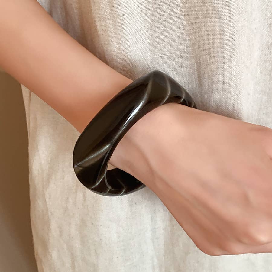 Stylish black cat eye resin bracelet displayed on a wrist with a twist design