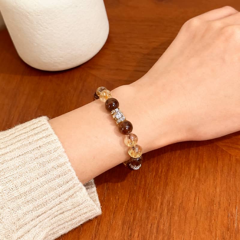 Black gold super seven crystal bracelet worn on a wrist with a cozy sweater
