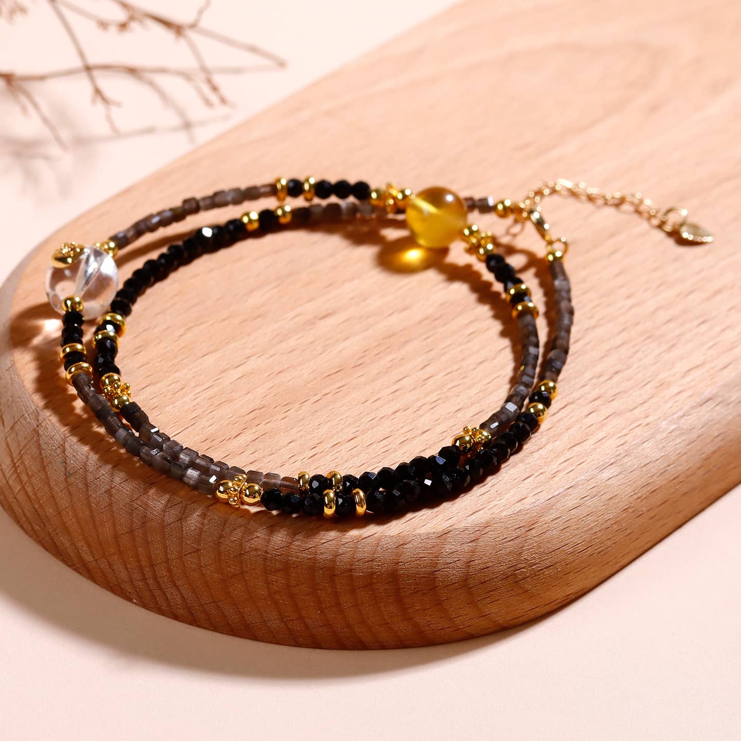 5 Senses black obsidian spinel anxiety choker featuring gemstone beads and gold accents on a wooden surface