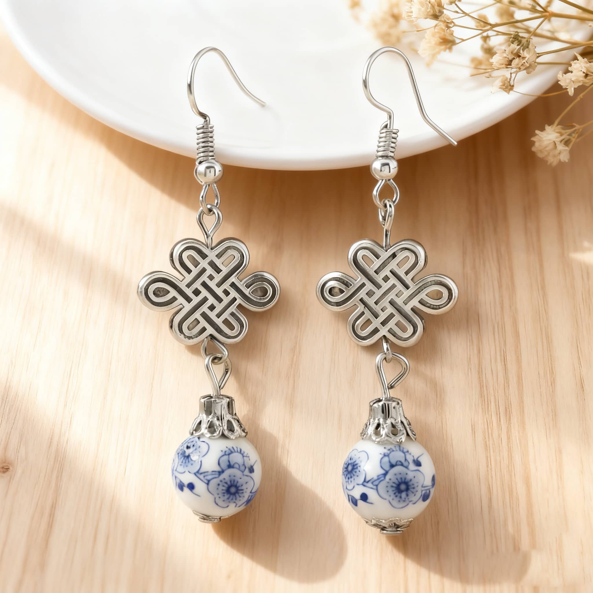 Elegant blue and white ceramic knot earrings with silver accents and intricate design