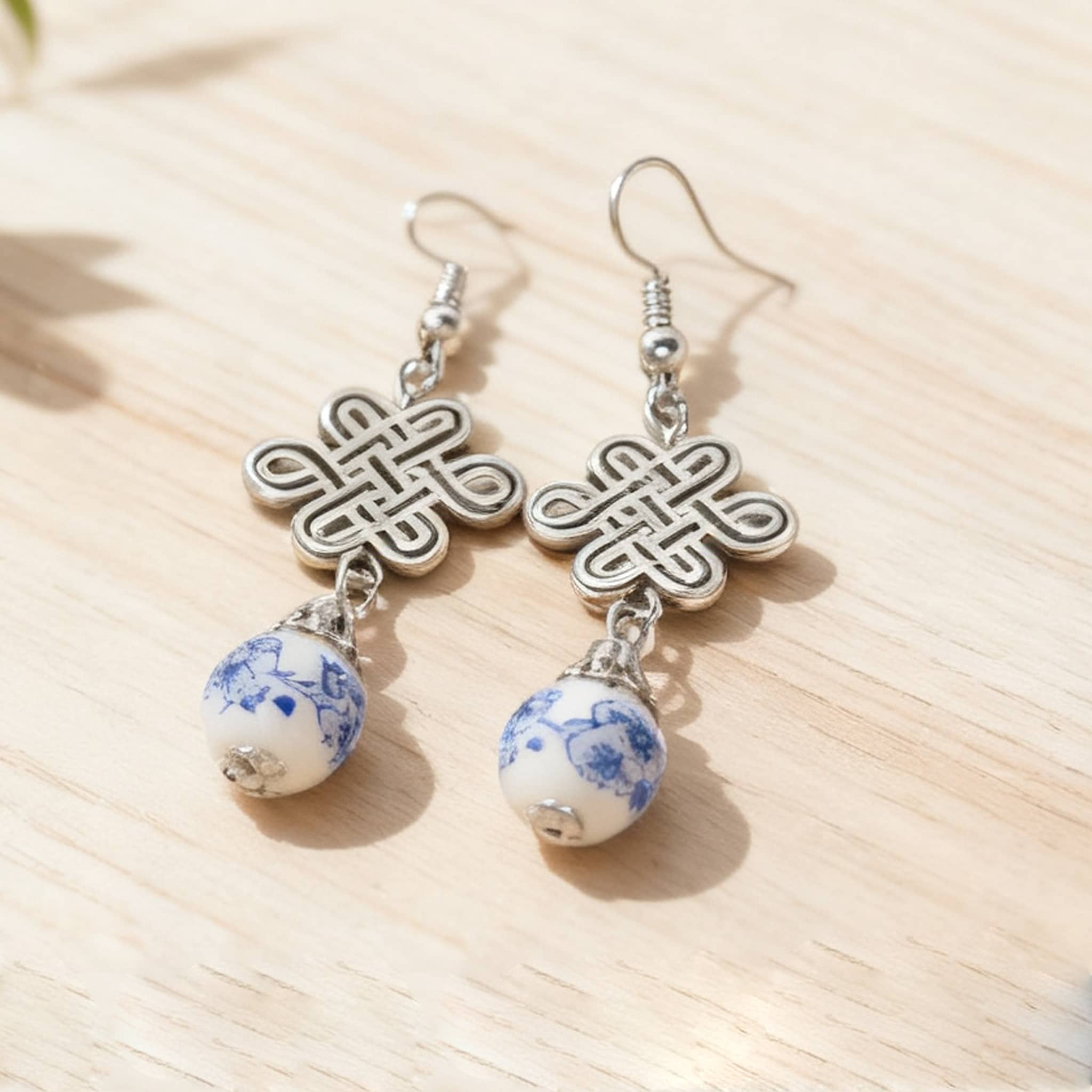 Blue and white ceramic knot earrings featuring intricate designs and dangling beads