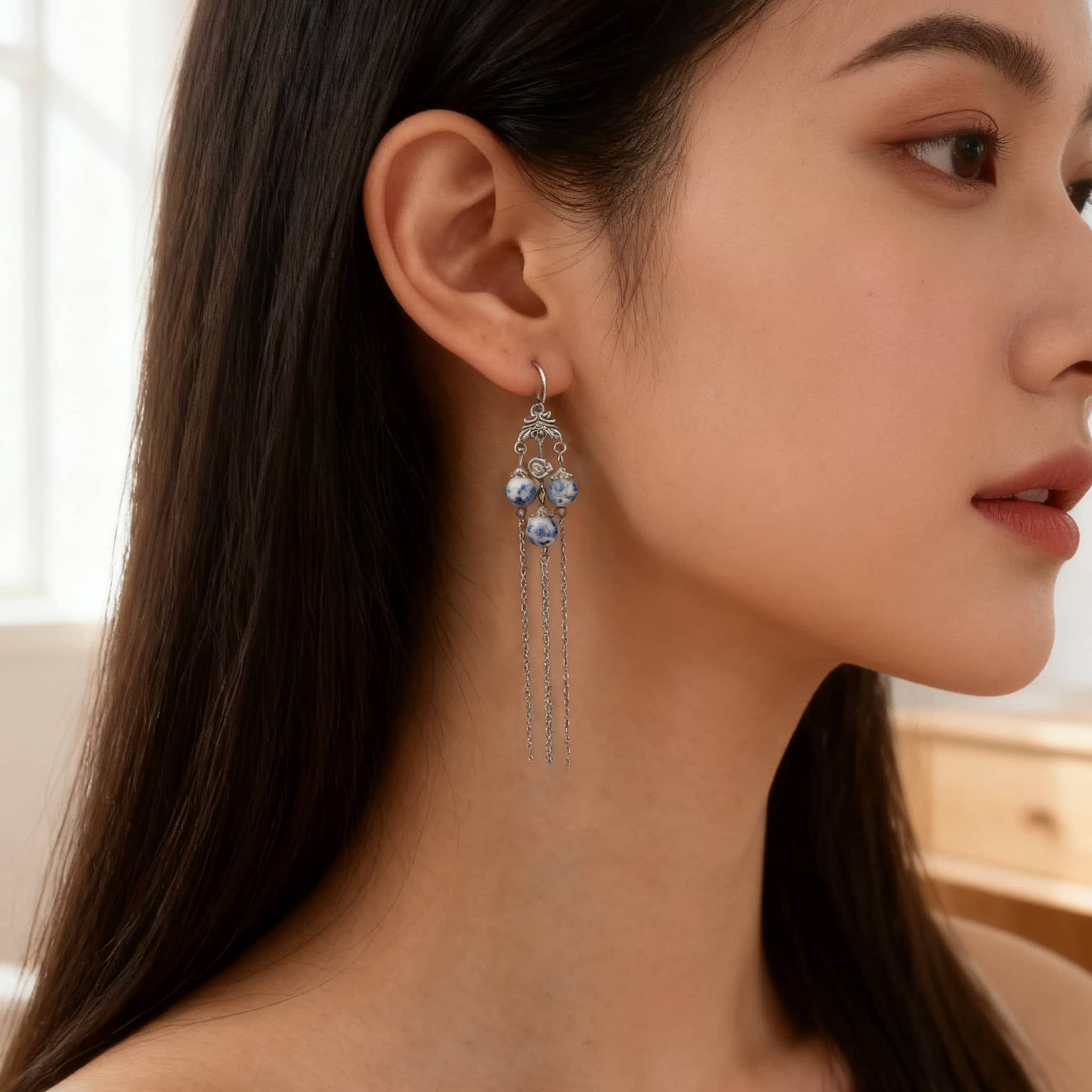 Elegant blue and white porcelain tassel earrings hanging elegantly on a model's ear