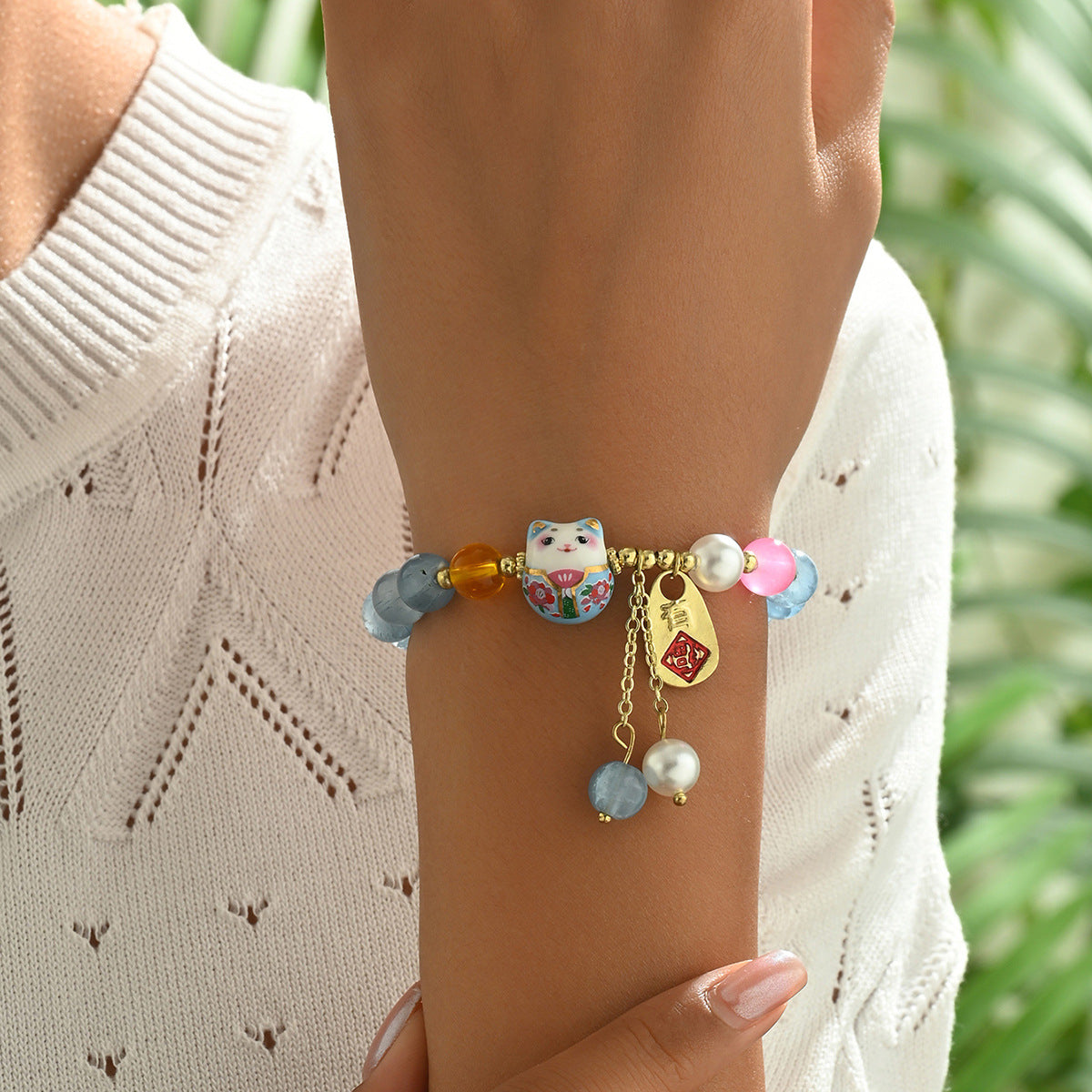 Blue crystal luck bracelet with colorful beads and cat charm worn on wrist