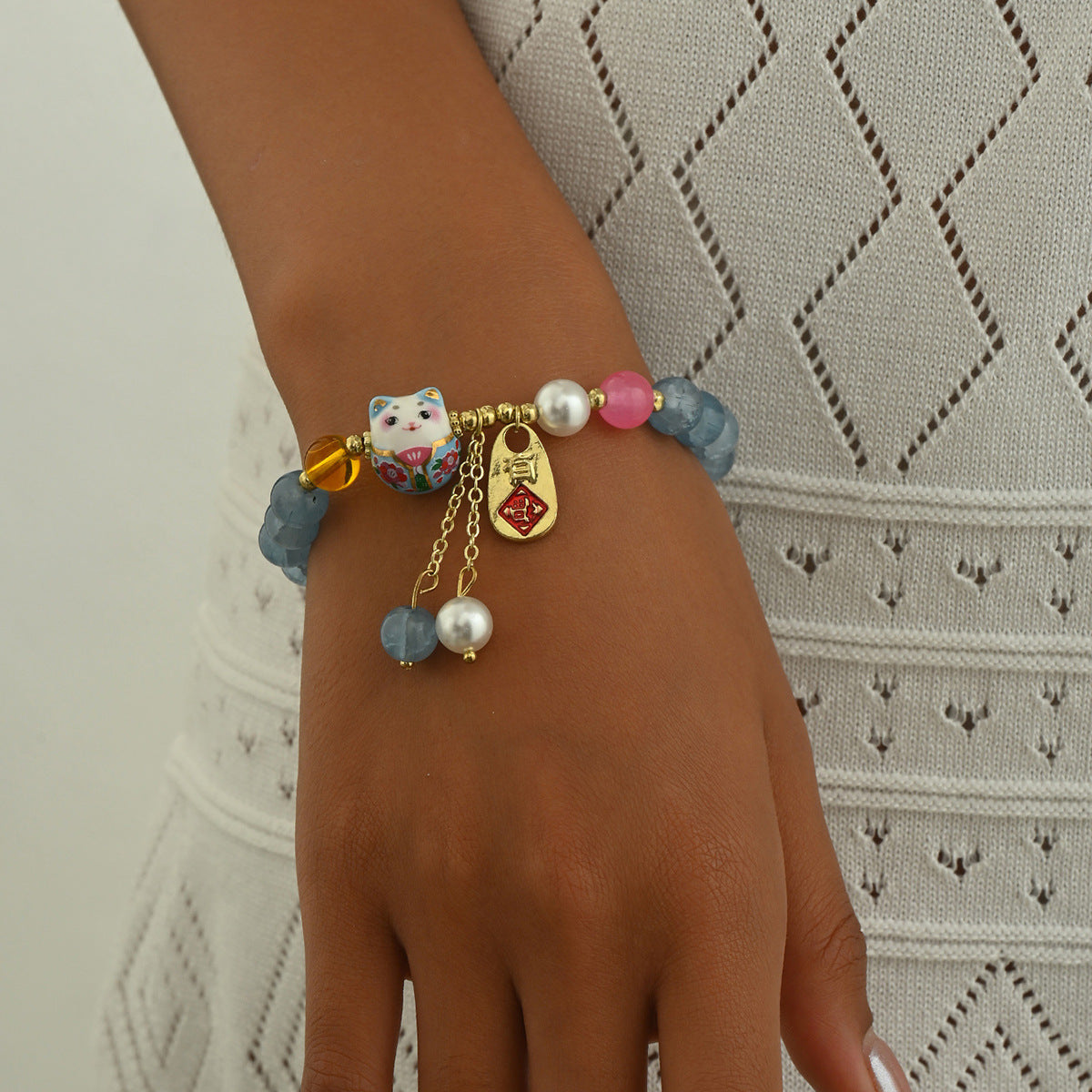 Blue crystal luck bracelet with cat charm pearl beads and gold accents on wrist