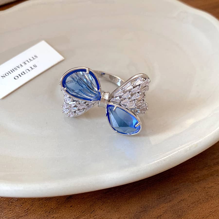 Elegant blue zircon bow ring adorned with sparkling accents on a simple plate