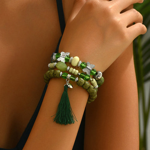 Green beaded bracelet trio stacked on wrist with tassel charm silver butterfly accents and mixed stone beads
