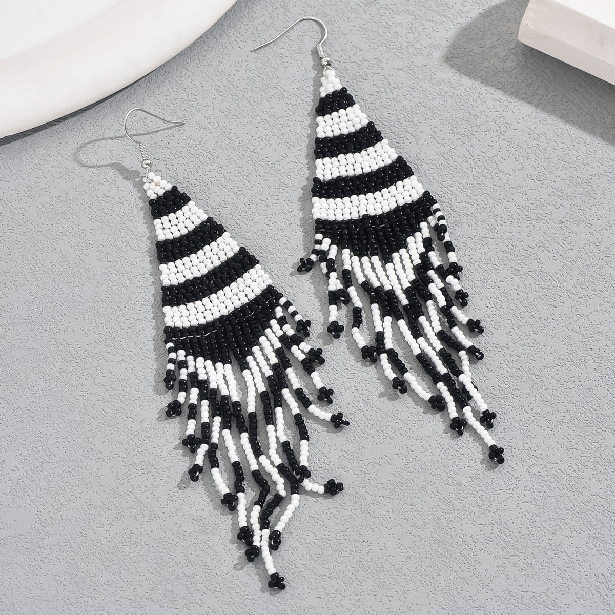 Handmade black and white seed bead earrings with bold striped pattern and fringe for boho and evening wear