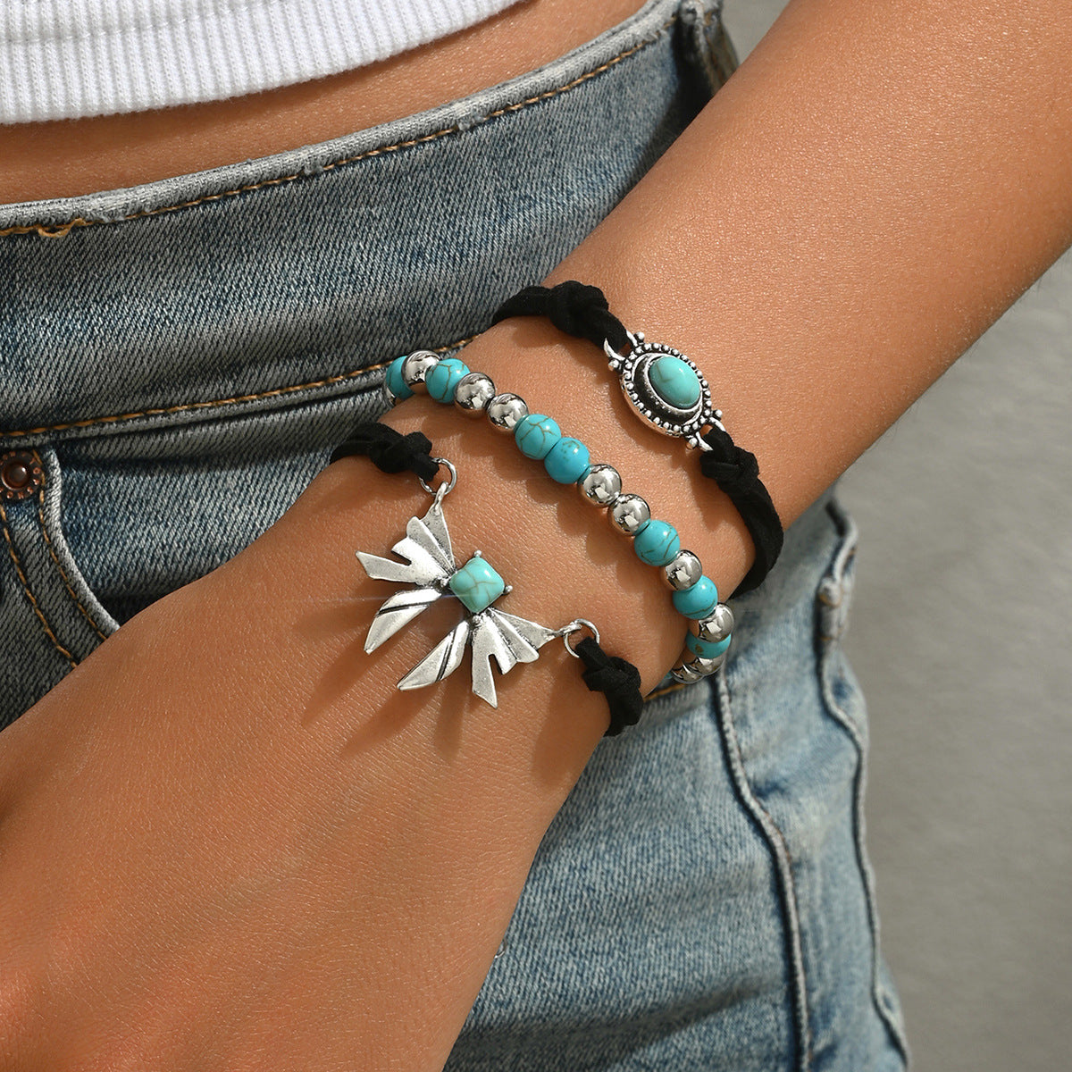 geometric butterfly bracelet set of three turquoise and silver beaded bracelets on wrist with black cord