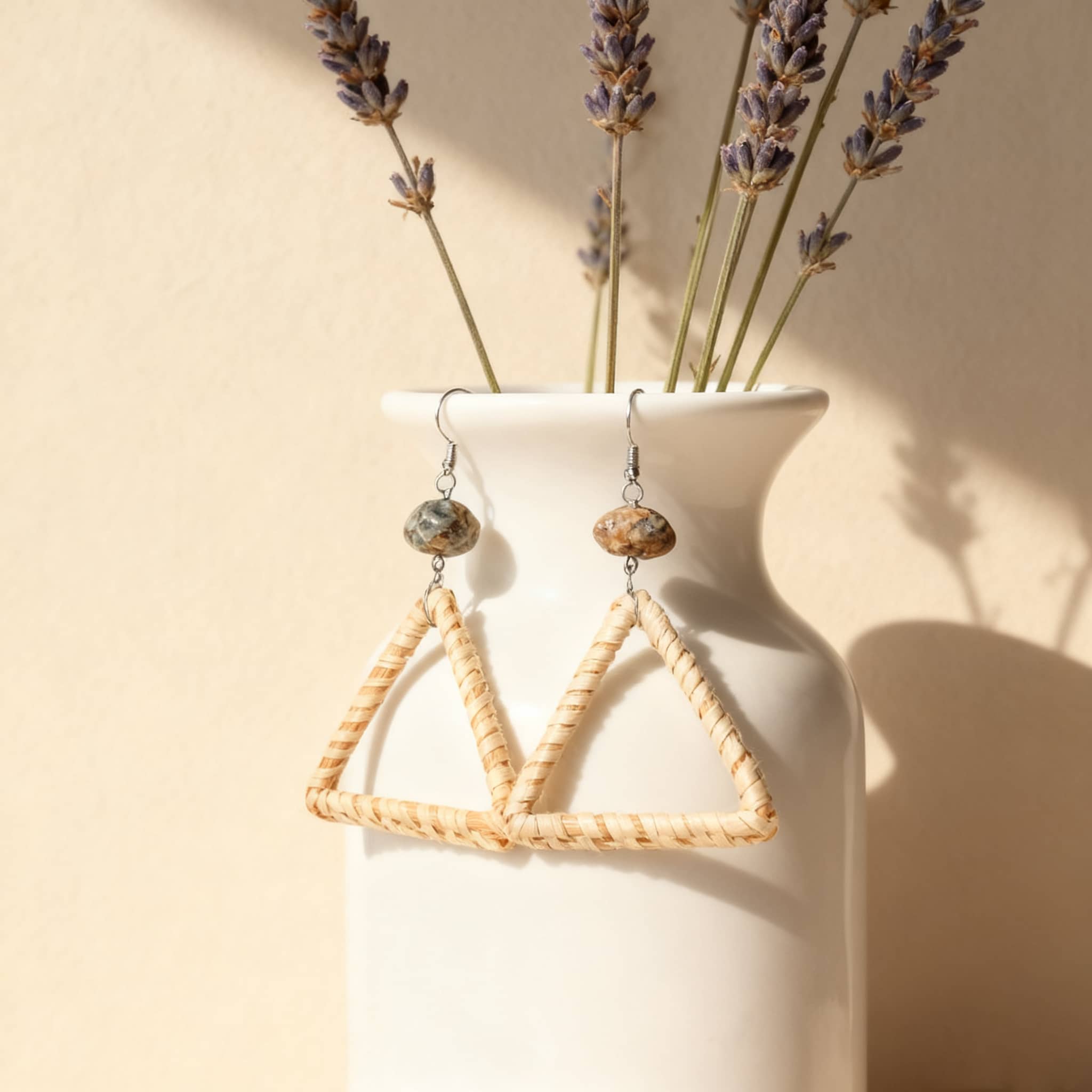 Calm woven triangle earrings displayed with floral arrangement in a white vase