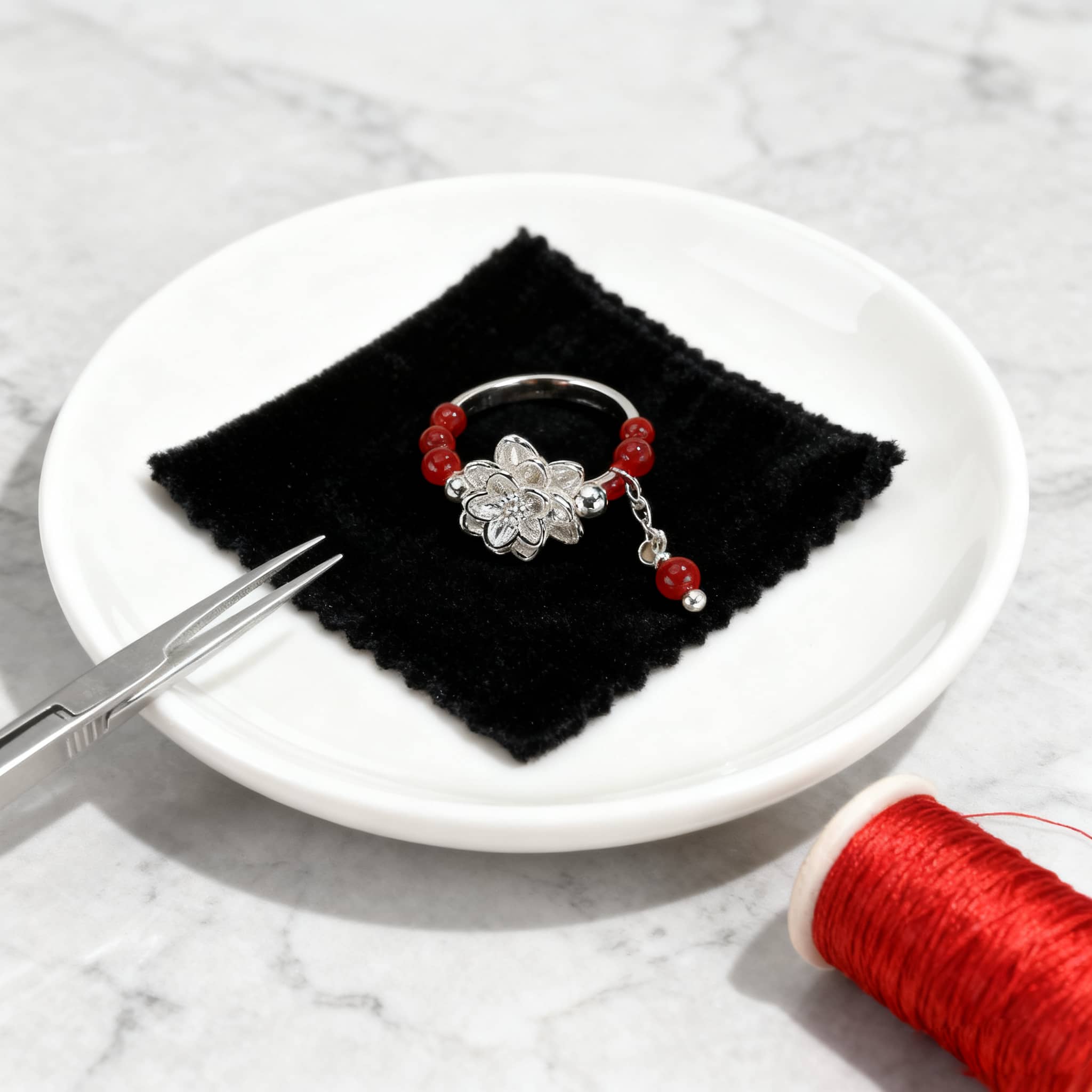 Anxious carnelian anxiety relief ring with decorative floral charm and red beads on a black cloth
