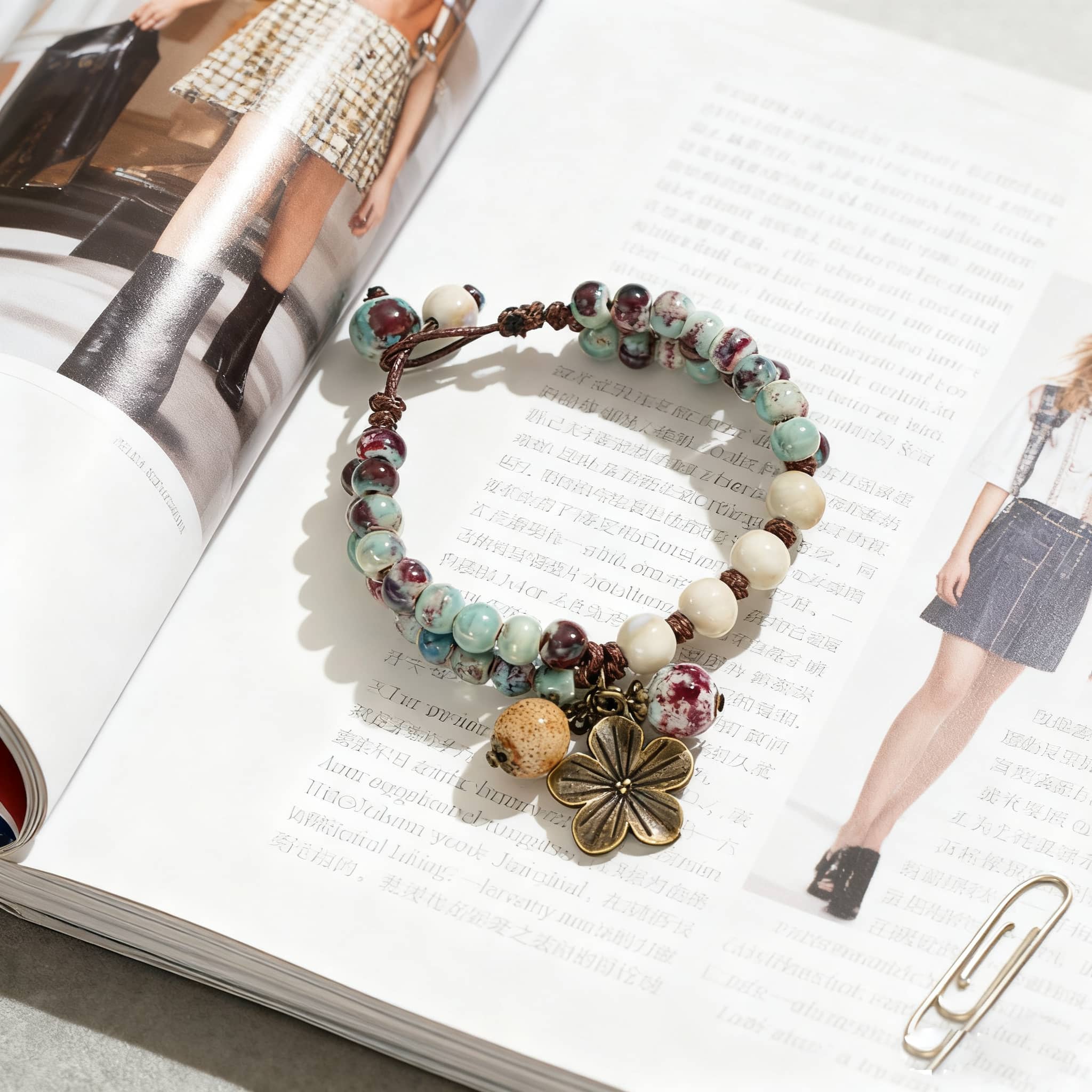 Ceramic floral charm bracelet with assorted beads and a flower charm on an open magazine