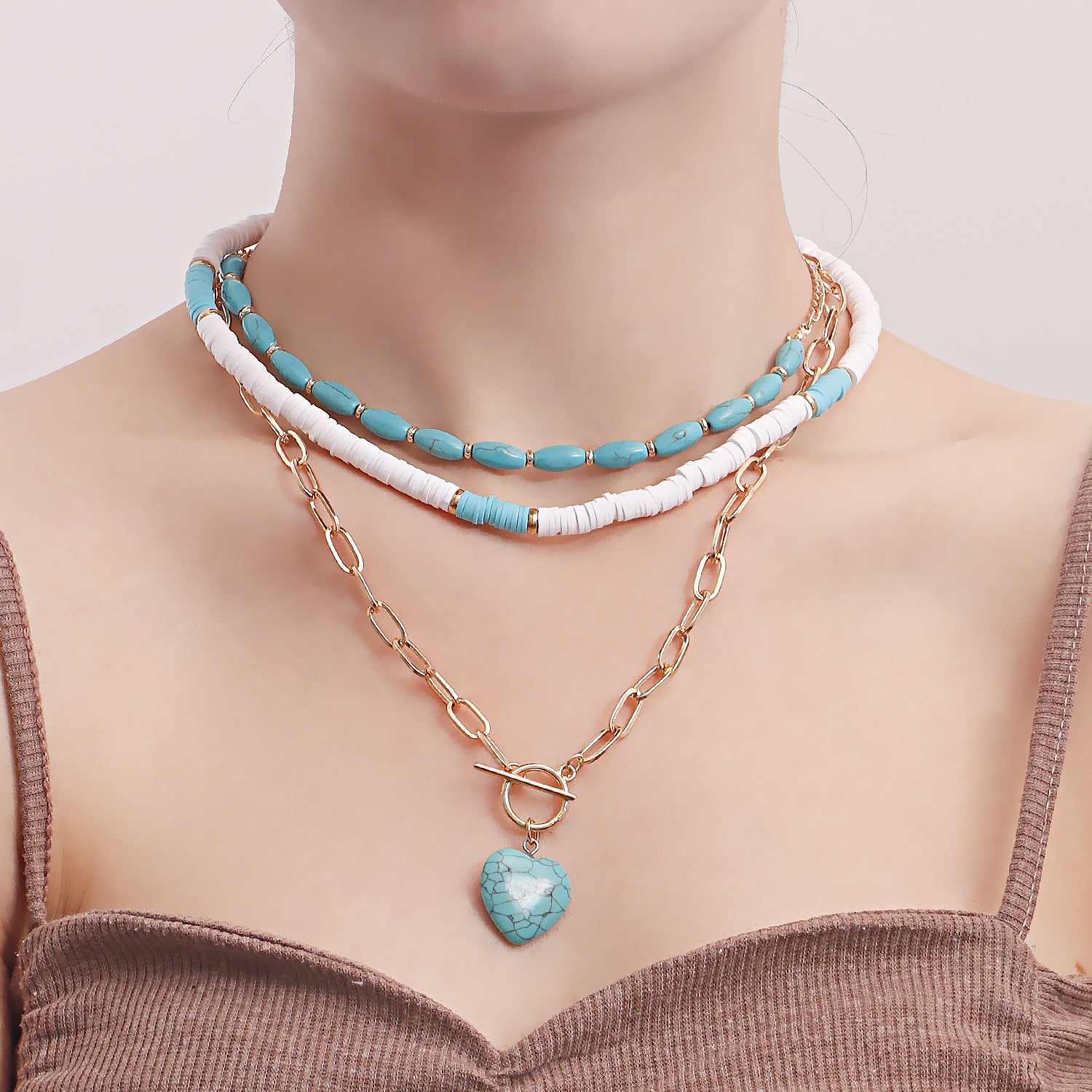 Layered necklace set featuring blue and white beads with clay heart pendant jewelry on model