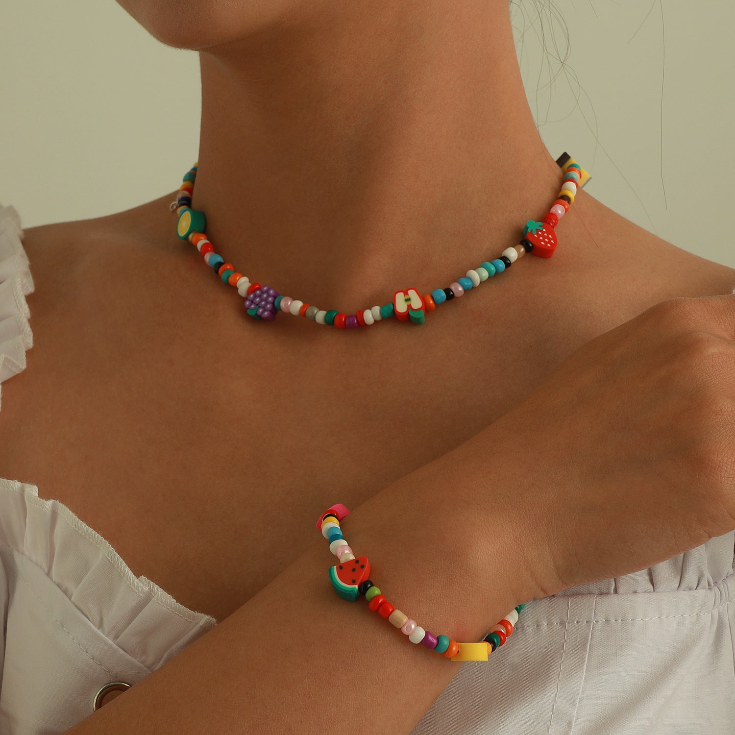 Colorful beaded necklace and bracelet with fruit charms worn on neck and wrist