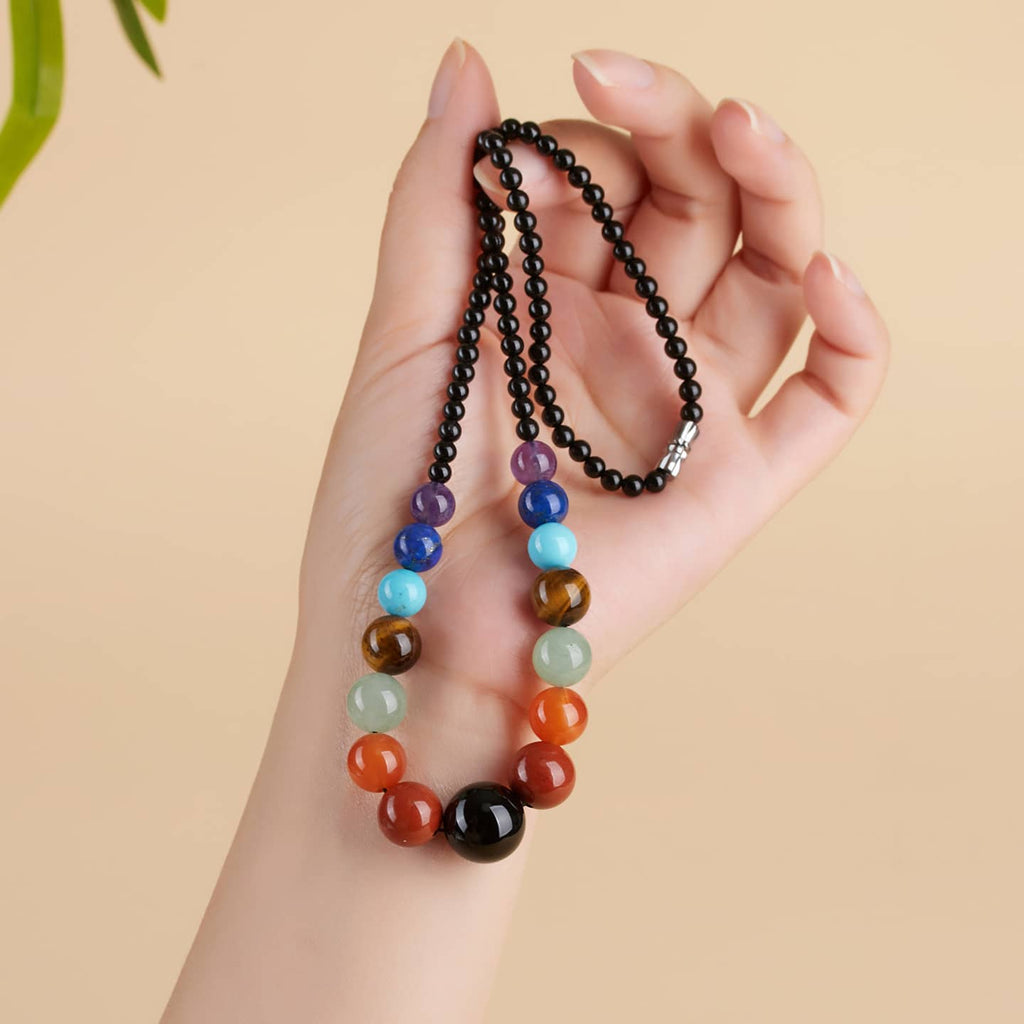 Hand holding a crystal necklace for stress and self care featuring colorful beads for calming energy