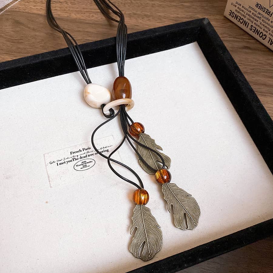 Unique earth pendant necklace with feather charms and decorative beads for a stylish look