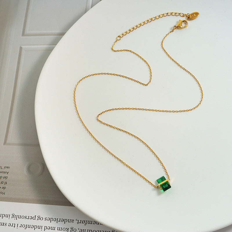 Calm necklace featuring a delicate gold chain with a small emerald green pendant necklace centerpiece