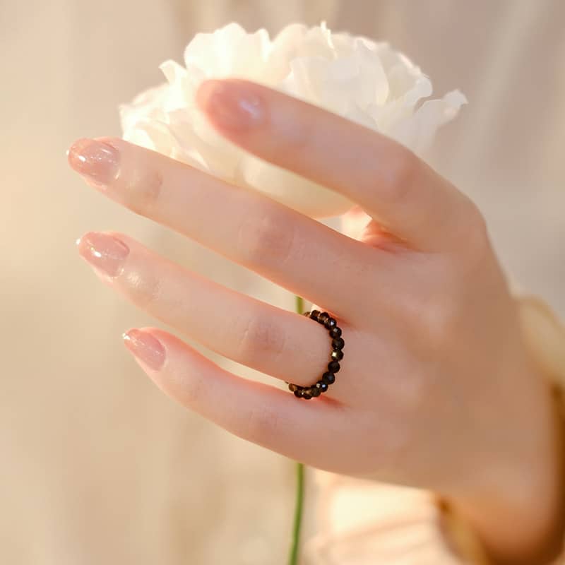 Elegant 5 Senses emotional support gemstone ring worn on a hand holding a white flower